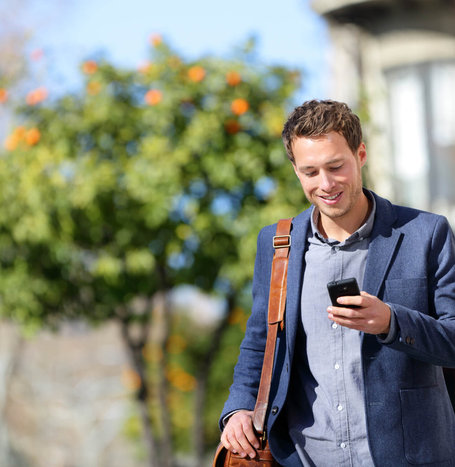 man walking outside and smiling at phone